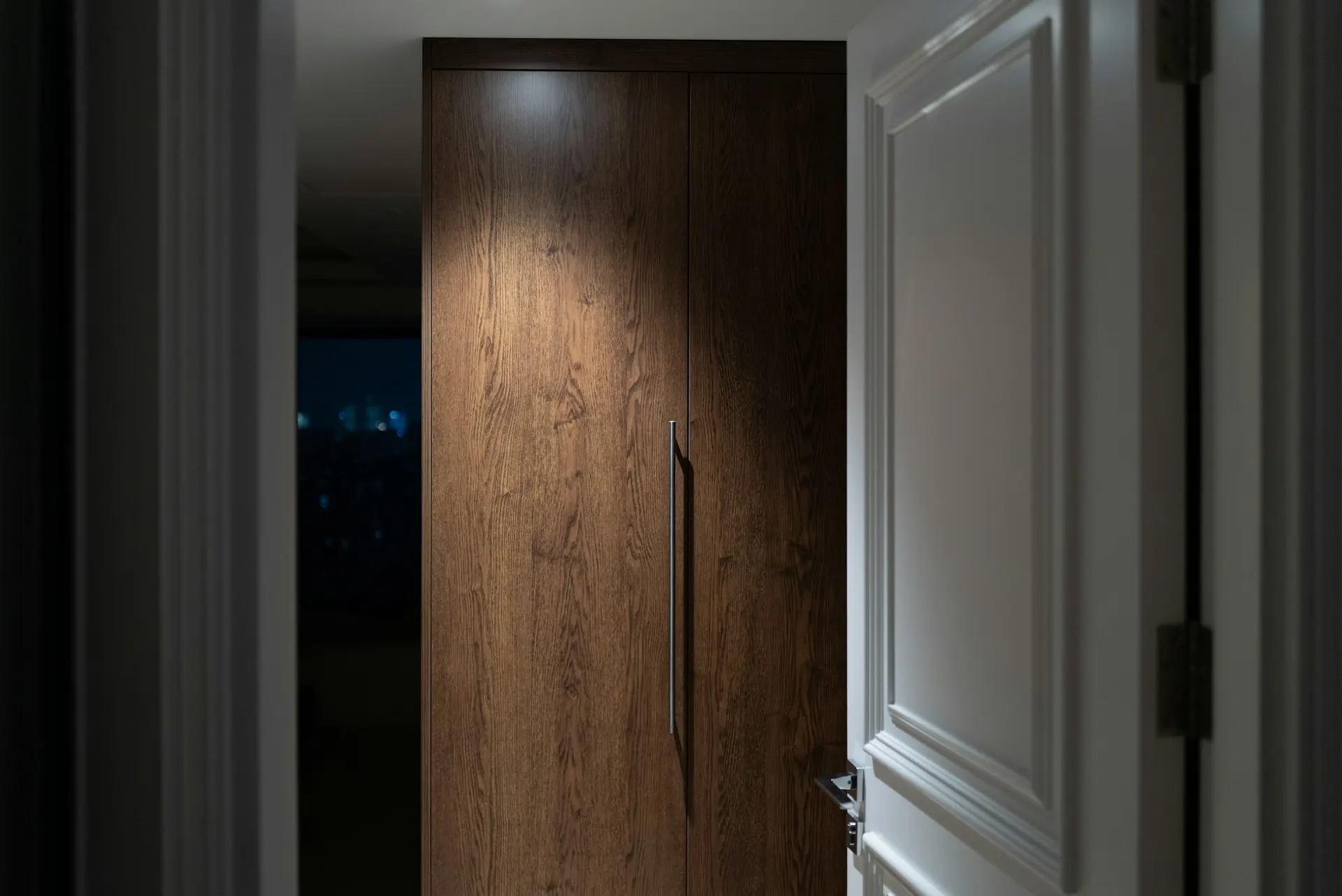 A modern wood front door lit by a single spotlight